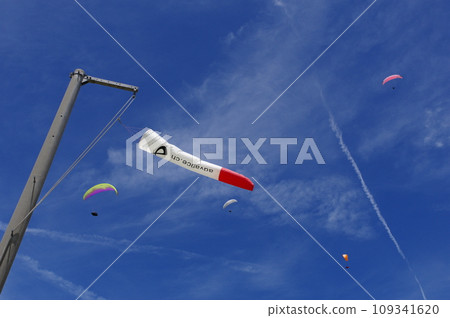 Streamers shining against the blue sky and paragliders flying above 109341620