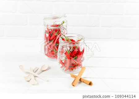 Spices seasoning chili pepper in glass bottle and cinnamon on table 109344114