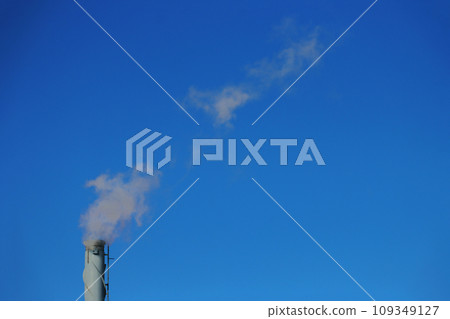 Pipe with white smoke against a blue sky. 109349127