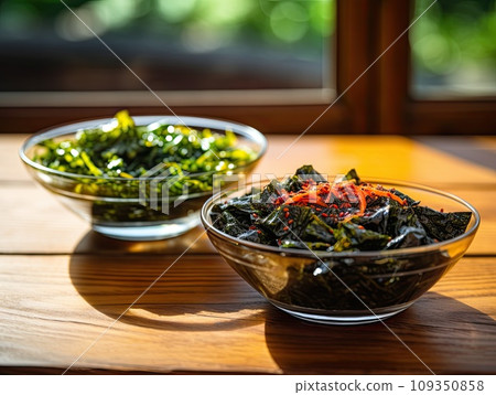 Japanese raw vegan organic delicious and tasty marinated chuka wakame salad and seaweed nori salad dishes in glass bowls on a wooden table Japanese raw vegan organic delicious and tasty marinated chuka wakame salad and seaweed nori salad dishes in glass bowls on a wooden table 109350858