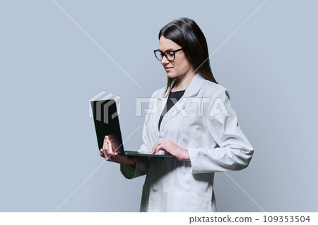 Woman medical scientist, pharmacist in white coat using laptop on grey background 109353504