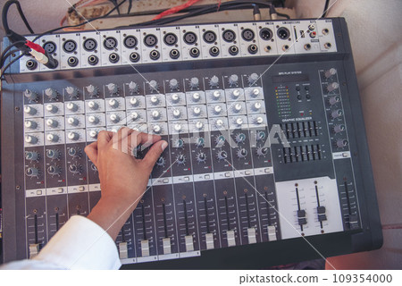 Production sound engineer woman hands adjusting volume equalizer voice, mixing console. DJ sound engineering working on recording studio mixing voice control. Producer remix tune music sound record Production sound engineer woman hands adjusting volume equalizer voice, mixing console. DJ sound engineering working on recording studio mixing voice control. Producer remix tune music sound record 109354000