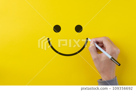 Customer review satisfaction feedback survey concept. Hand using pen to draw happy smiling face on yellow background. Service product evaluation business, Positive thinking, Mental health assessment, 109356692