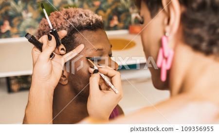 African transgender man with his eyes closed as a colleague applies make-up African transgender man with his eyes closed as a colleague applies make-up 109356955