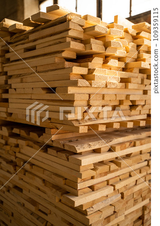 Wood processing. Stacked wooden boards at lumber warehouse in a woodworking industry. Stacks with pine lumber. Raw wood drying in the lumber warehouse. 109359115