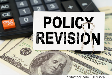 On the dollars there is a calculator and a business card with the inscription - policy revision On the dollars there is a calculator and a business card with the inscription - policy revision 109359759