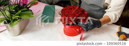 Close up of florist in flower shop make roses compositions for holiday. Family flower's business 109360516