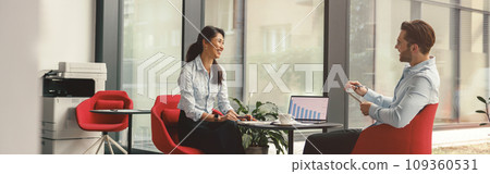 Two diverse business colleagues working together on project sitting in modern meeting room 109360531