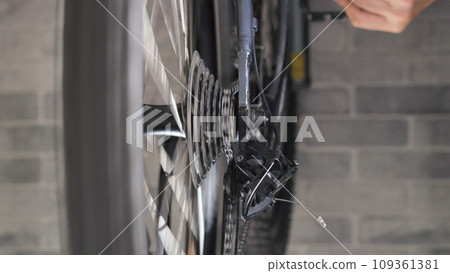 Close-up of the rotating brake disc and spokes of a mountain bike. Repair and maintenance of a bicycle in a specialised workshop. Close-up of the rotating brake disc and spokes of a mountain bike. Repair and maintenance of a bicycle in a specialised workshop. 109361381