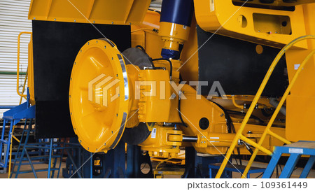 Brake disc with calipers on a dump truck assembly line in a workshop for the production of large yellow quarry trucks. Shop of the plant. Close-up. Brake disc with calipers on a dump truck assembly line in a workshop for the production of large yellow quarry trucks. Shop of the plant. Close-up. 109361449