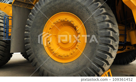 Close-up of a large car wheel. Tyres of a dump truck. A huge wheel on a yellow lorry. Close-up of a large car wheel. Tyres of a dump truck. A huge wheel on a yellow lorry. 109361452