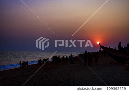 Silhouette of beach life Scene on a clear dusk with orange Sun behind a couple at renowned Indian seashore of Puri, Odisha, India,Asia. 12th February 2020. 109362359