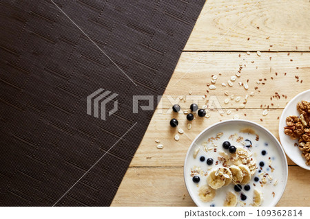 Oatmeal porridge with banana, walnuts and honey in bowl on wooden background. Healthy breakfast. Oatmeal porridge with banana, walnuts and honey in bowl on wooden background. Healthy breakfast. 109362814