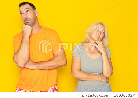 Contemplation of two lovers caucasian 40s couple spouses wife and husband boyfriend and girlfriend looking upwards, planning for future, thoughtful and pensive people isolated in yellow Contemplation of two lovers caucasian 40s couple spouses wife and husband boyfriend and girlfriend looking upwards, planning for future, thoughtful and pensive people isolated in yellow 109363027