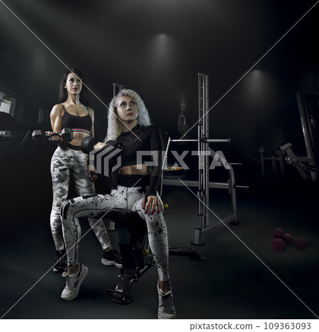 fitness bodybuilding a couple of beautiful girls do sports together with a trainer with a beautiful body and a slim figure pose in the gym, creative photo. High quality photo 109363093