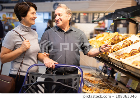 Couple chooses sweet puffs in bakery Couple chooses sweet puffs in bakery 109363346