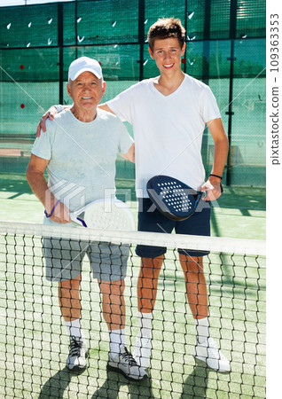 Senior man and young man posing on padel court Senior man and young man posing on padel court 109363353