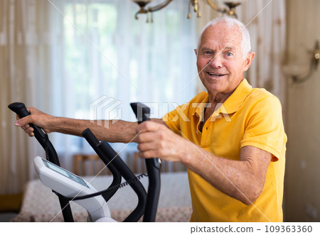 Senior man with elliptical trainer at home Senior man with elliptical trainer at home 109363360