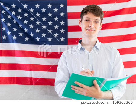 Young guy making notes against background of USA flag Young guy making notes against background of USA flag 109363366