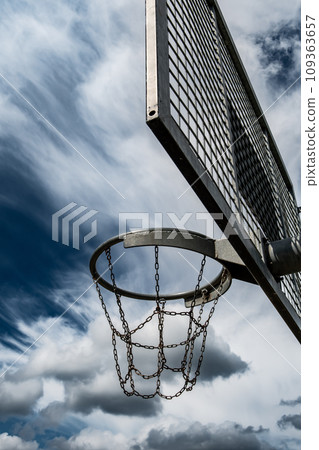 Metal Basketball Board And Ring With Chains In Front Of Sky With Heavy Clouds 109363657