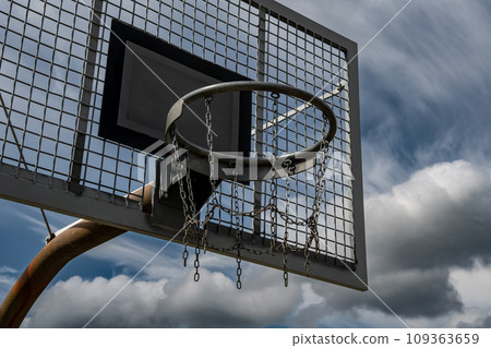 Metal Basketball Board And Ring With Chains In Front Of Sky With Heavy Clouds Metal Basketball Board And Ring With Chains In Front Of Sky With Heavy Clouds 109363659