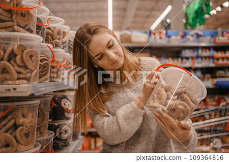 Stack of Chocolate Santa Clauses. Christmas time. A young woman chooses a gift set for Christmas to a child on a supermarket shelf. 109364816