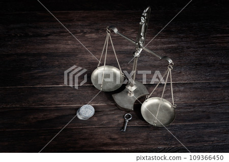 Bronze traditional balance scale and silver dollar coins with key on wooden table Bronze traditional balance scale and silver dollar coins with key on wooden table 109366450