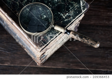 Vintage magnifying glass with books on table Vintage magnifying glass with books on table 109366453