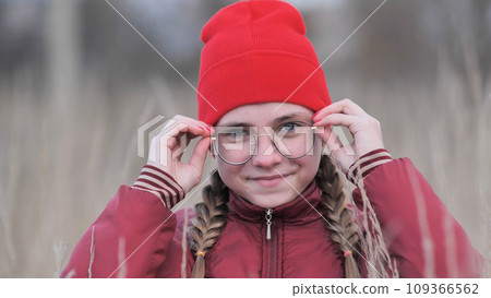 Portrait of a teenage girl in glasses standing in tall grass in the fall. Portrait of a teenage girl in glasses standing in tall grass in the fall. 109366562