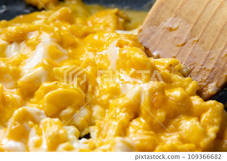 A cooking scene of frying beaten eggs in a frying pan. 109366682