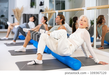 Group of different people doing exercises with roller 109367120