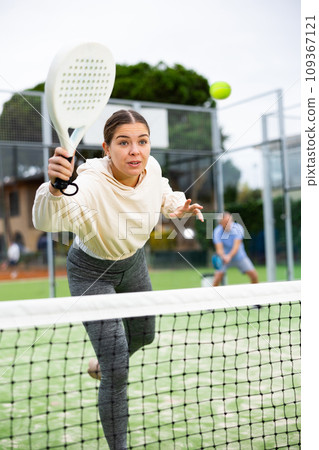 Sporty young girl playing padel on open court 109367121