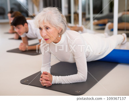 Women and men practicing yoga positions during group training in fitness center, performing stretching asana Urdhva Mukha Shvanasana 109367137