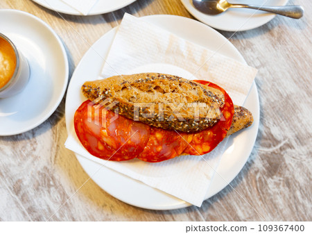 Typical spanish breakfast is smoked sausage sandwich on crispy bun Typical spanish breakfast is smoked sausage sandwich on crispy bun 109367400