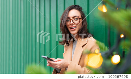 Woman hold smartphone leanin wall looking at Woman hold smartphone leanin wall looking at 109367498