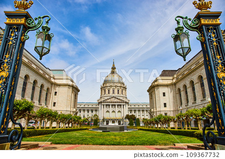 City hall with green courtyard framed by golden gilded lampposts with cloudy blue sky City hall with green courtyard framed by golden gilded lampposts with cloudy blue sky 109367732