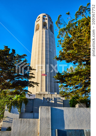 Coit Tower with memorial and American Flag under cerulean blue sky 109367752