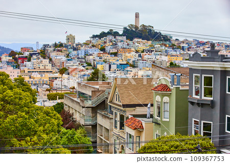 Close up of colorful buildings with telephone wires leading to Coit Tower in distance 109367753