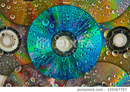 Colorful and vibrant blue CD surface with water drops stacked on top of pile of CDs abstract art Colorful and vibrant blue CD surface with water drops stacked on top of pile of CDs abstract art 109367767