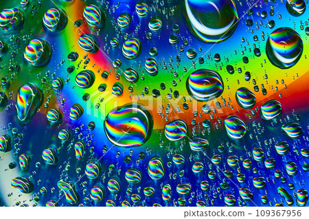 Swirls of rainbow colors inside wobbly bubbles on dark silvery blue rainbow burst background asset 109367956
