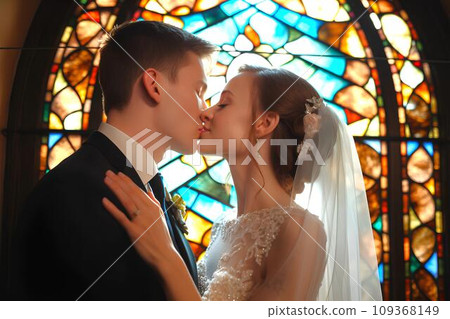 A white couple kissing their vows in front of stained glass, AI generated 109368149