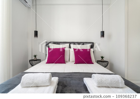 Double bed in the bright bedroom room interior furnishing furniture. Velour gray quilt with towels and hanging lamps. Double bed in the bright bedroom room interior furnishing furniture. Velour gray quilt with towels and hanging lamps. 109368237