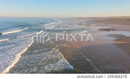 A low flyover of a drone over a surfer in the sea as he overcomes the waves. 109368278
