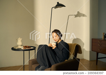 A woman relaxing on a sofa at sunset 109368397