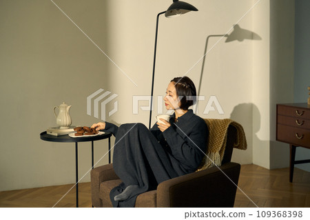 A woman relaxing on a sofa at sunset 109368398