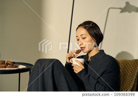 A woman relaxing on a sofa at sunset A woman relaxing on a sofa at sunset 109368399