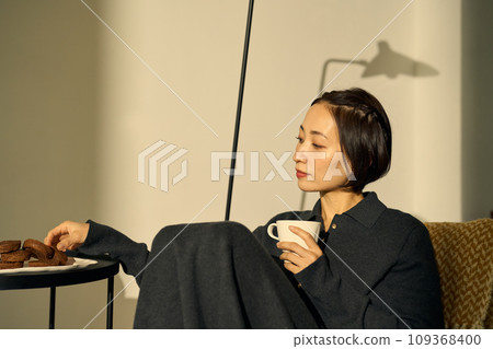 A woman relaxing on a sofa at sunset 109368400
