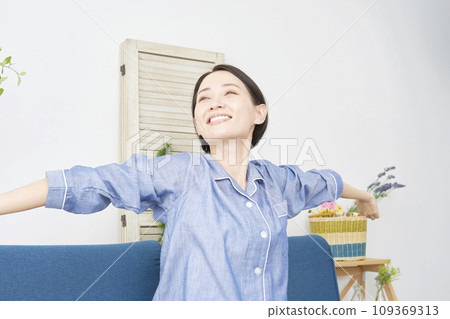 一名中年婦女在家中穿著睡衣伸展身體 109369313