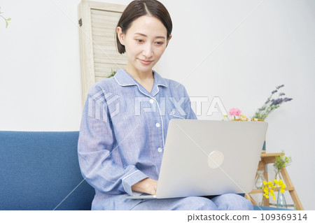 一位穿著睡衣並在家使用筆記型電腦的中年婦女 109369314