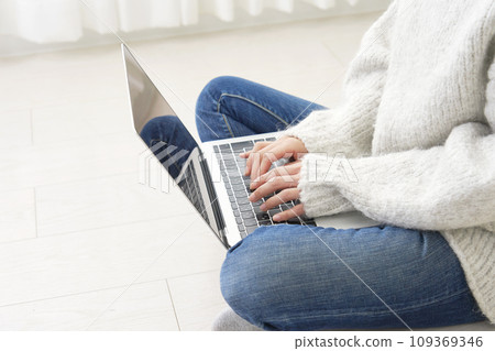 A woman who uses a laptop in the living room without a face A woman who uses a laptop in the living room without a face 109369346
